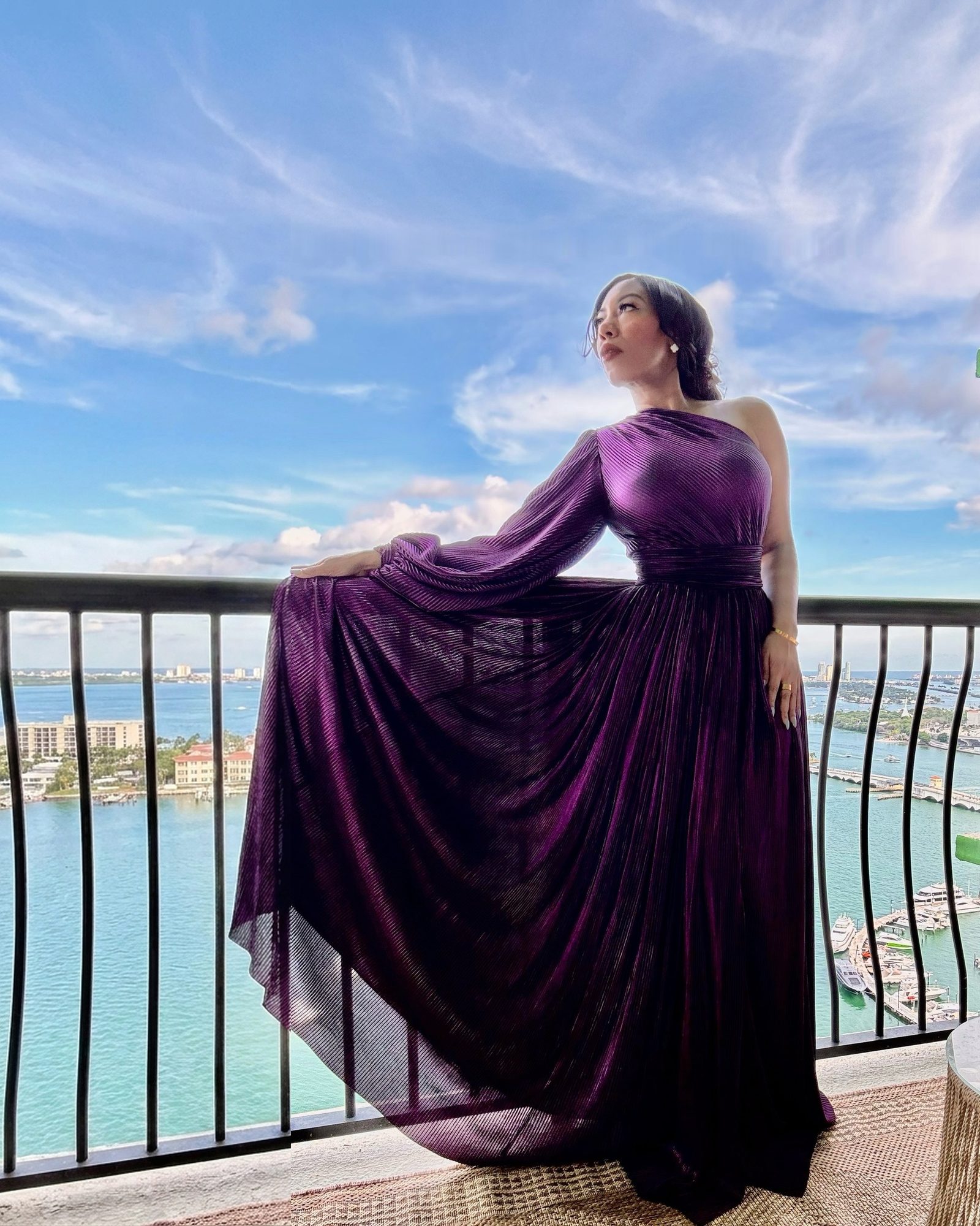 Chilen Moya on a balcony overlooking the bay, wearing a flowing violet gown